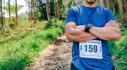 Young male trail athlete posing with race number placed outdoors