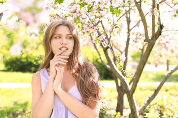 Beautiful young woman near blooming tree on spring day