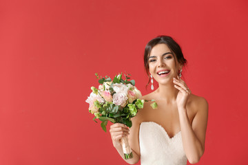 Beautiful young bride with bouquet of flowers on color background