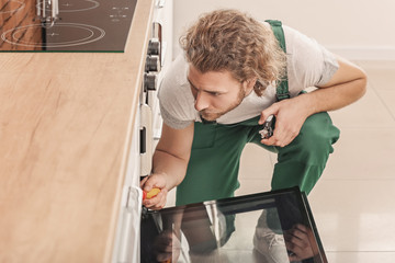 Worker repairing oven in kitchen