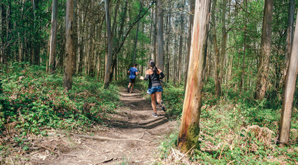 Young woman and man participating in a trail race through the forest © David Pereiras
