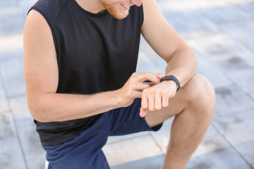 Sporty young man checking his pulse outdoors