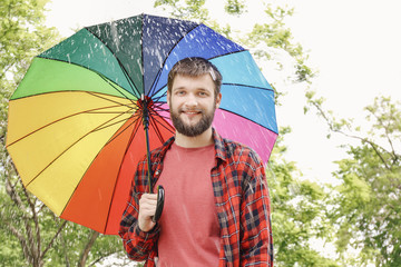 Handsome man with colorful umbrella outdoors