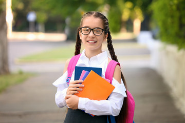 Cute little schoolgirl after classes outdoors