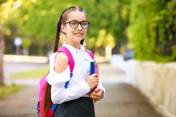 Cute little schoolgirl after classes outdoors