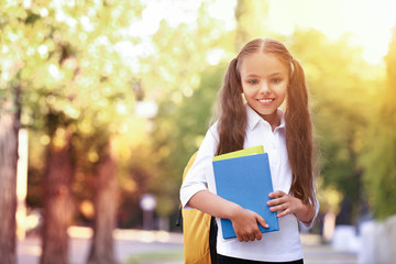 Cute little schoolgirl after classes outdoors