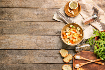 Bowl of tasty soup with bread and spices on wooden table