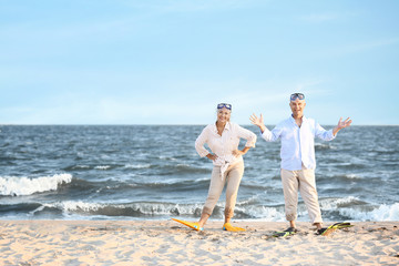 Fototapeta na wymiar Happy mature couple with snorkeling masks and paddles having fun at sea resort