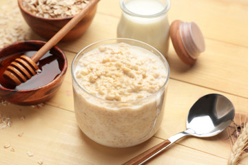 Tasty oatmeal with milk and honey on wooden table