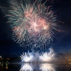 Beautiful pyrotechnic fireworks at night over the water. Celebration.