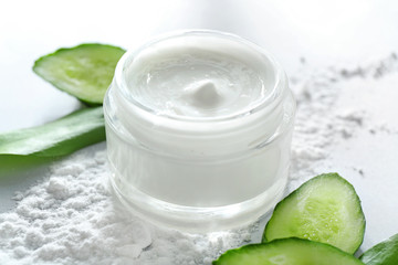 Obraz na płótnie Canvas Jar of body cream and cucumber slices on white background, closeup
