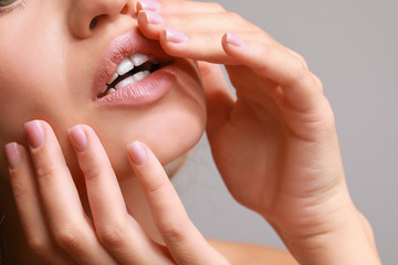 Beautiful young woman on grey background, closeup