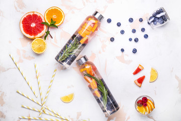 Bottles of tasty infused water on light background