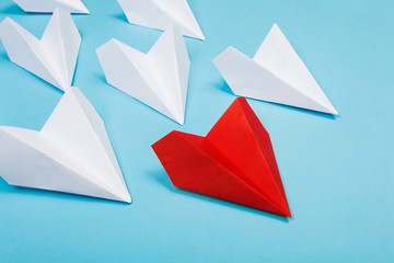 Group of white paper plane in one direction and one red paper plane pointing in different way on blue background. Business for innovative