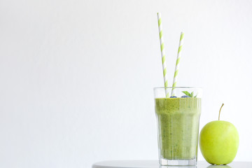 Glass of tasty smoothie with apple on table against white background
