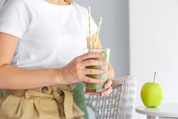 Young woman with tasty smoothie in glass at home