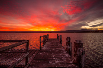 Burning red sunset  on the lake with timber jetty