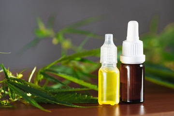Hemp plant herbal pharmaceutical CBD oil from jar. CBD oil bottles cannabis extract tincture liquid on wooden table. Medical marijuana concept
