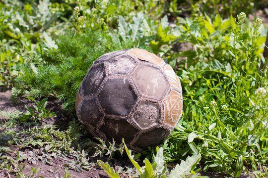 An old, tacky soccer ball is lying on the grass. The end of the game of football.