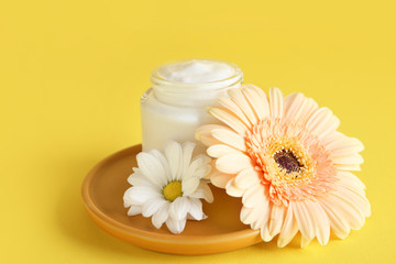 Fototapeta na wymiar Body cream with flowers on color background