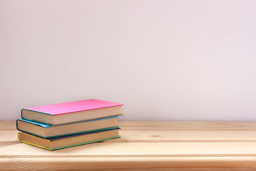 Textbooks in color covers on a wooden table, space for Your text.