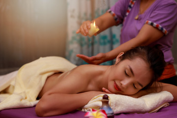 Asian woman enjoying a salt scrub massage at spa.