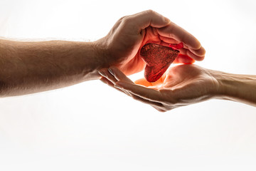 Female and male hands are keeping red heart together. Heart is between hands. World Compassion Day.