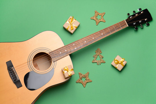 Guitar and Christmas decor on color background