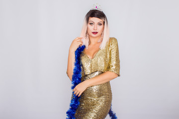 Emotional happy blonde woman in evening gold dress and with tinsel on her neck.