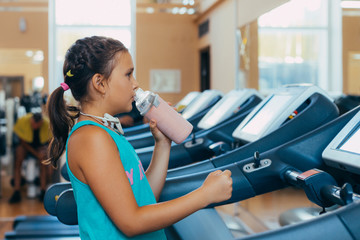 .little beautiful girl with a smile runs on a trainer in the gym