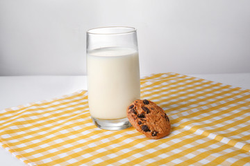 Glass of fresh milk and cookie on table