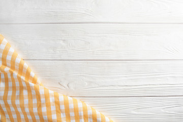 Checkered napkin on white wooden surface, top view