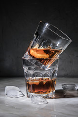 Glasses of whiskey and ice cubes on table