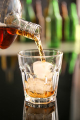 Pouring of whiskey in glass on table