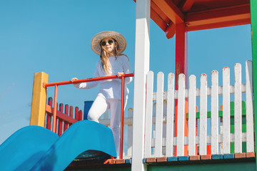 girl with sunglasses and hat on playground