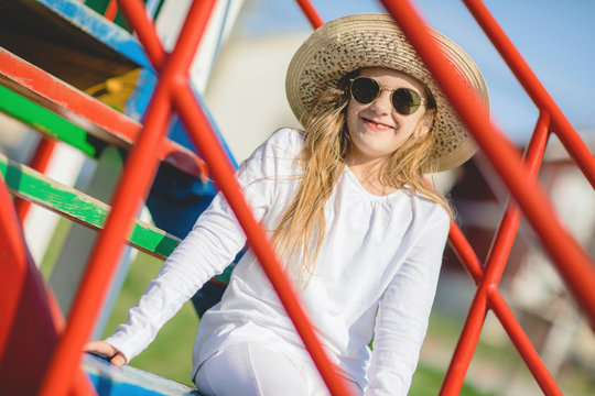 stylish little girl with sunglasses and hat on playground