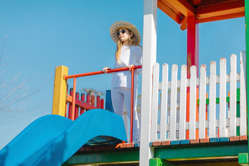 Young stylish girl on slide at playground