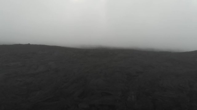 close up aerial of Mauna Loa lava field through fog,