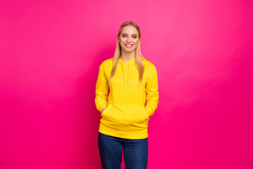 Amazing lady holding hands in pockets of yellow hoodie pullover isolated pink background