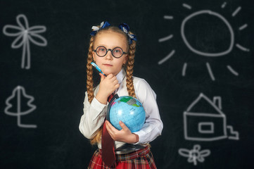 Portrait of a schoolgirl of initial classes with the globe . Initial education.  Back to school