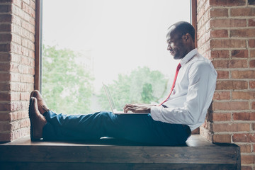 Photo of dark skin guy sitting on window talking skype with relatives wear elegant costume without...
