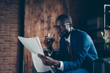Photo of dark skin macho guy sitting office sofa drinking alcohol beverage reading fresh press wear...