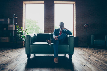 Full body photo of dark skin macho guy sitting office sofa wear specs and corporate costume
