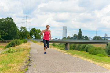 Athletic healthy woman jogging on a rural road