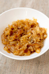 Homemade caramelized onions on a white plate, side view. Close-up.
