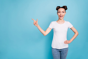 Beautiful lady with cute hairdo indicating finger empty space at cool price wear white casual t-shirt isolated blue background