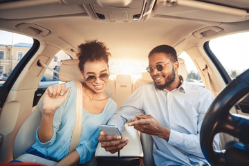 African-american couple using navigator app on phone in car