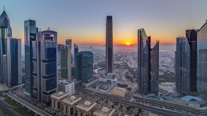 Fototapeta premium Sunrise over Dubai skyline in the morning, aerial top view to downtown city center landmarks timelapse.