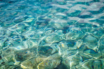 Fototapeta na wymiar Turquoise sea surface with transparent shallow water - pebbles, stones, rocks on the seabed