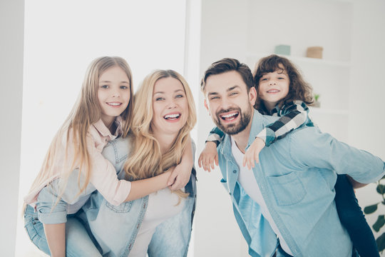 Photo Of Big Family Four Members Hugging Carry Little Children Piggy Back Indoors Apartments